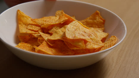 Close-Up-Of-Person-At-Home-Pouring-Tortilla-Or-Corn-Chips-From-Packet-Into-Bowl-On-Table